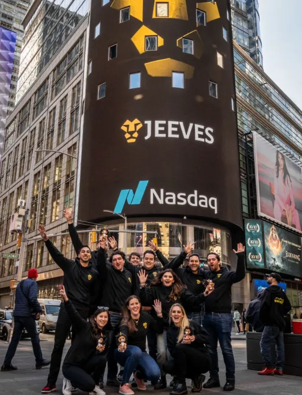 Equipo de Jeeves celebrando en Times Square frente a la pantalla de Nasdaq
